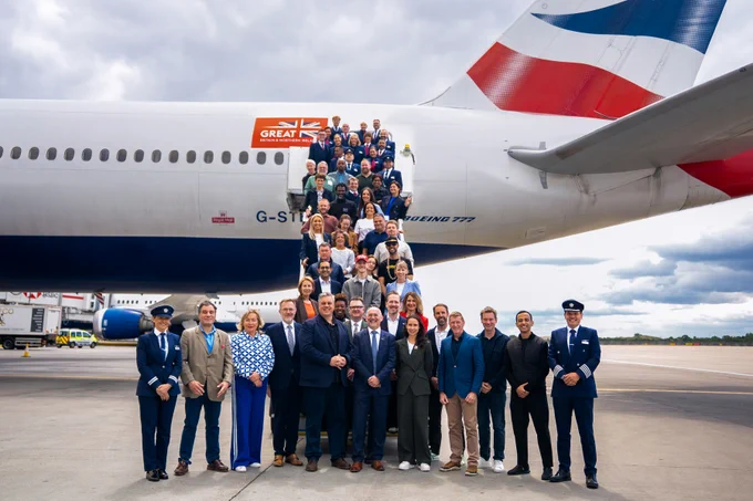 The delegation stands on the steps up to the airplane  for a group photo.