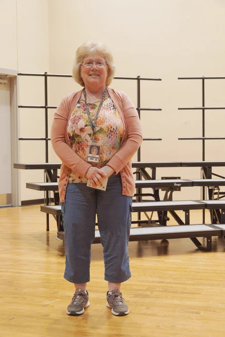 Karen Kuhr standing on stage at CHS with risers in background after accepting her 45 years of service pin.