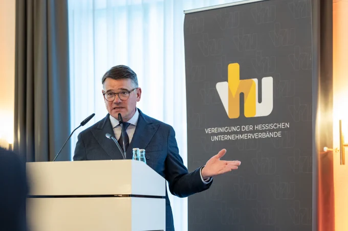 Ministerpräsident Boris Rhein steht an einem Rednerpult mit einem Logo der "Vereinigung der Hessischen Unternehmerverbände" darauf.