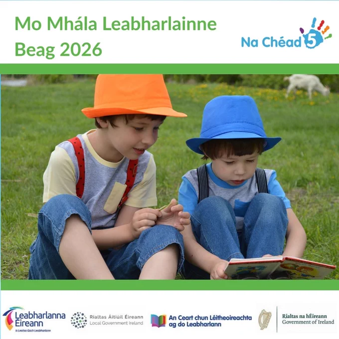 Photograph shows two young boys wearing colourful hats, sitting on the grass and reading a book together.

Above the photograph shows the title (translated to Irish) in green, "My Little Library Bag 2026" with the logo for First 5 Ireland beside it. 

Below the photograph shows the logos for Libraries Ireland, Local Government Ireland, Right to Read at Your Library, and Government of Ireland.