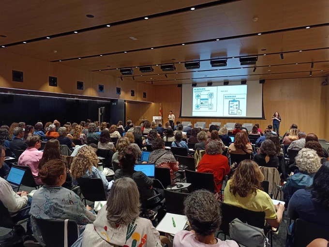 Públic assistent a una jornada en un auditori ple. 