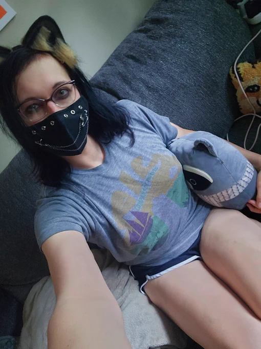 a selfie of me wearing raccoon ears, a face mask, sitting on the couch holding a plush raccoon with my thighs showing