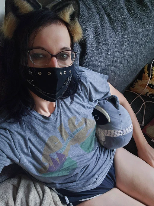 a selfie of me wearing raccoon ears, a face mask, sitting on the couch holding a plush raccoon with my thighs showing