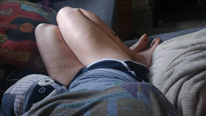 a photo from my POV looking down at my thighs. my legs are bent underneath me on the couch. there are pillows and blankets around me
