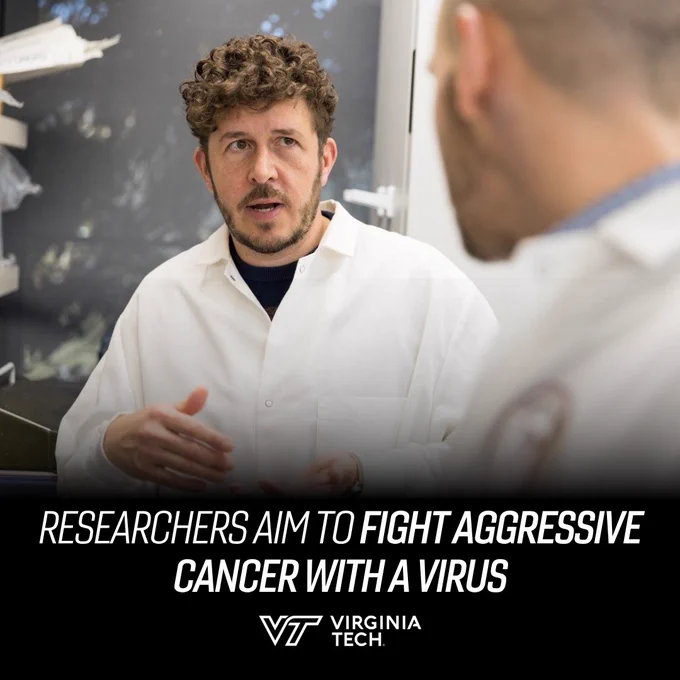 Two researchers engage in discussion. Text on screen reads: "researchers aim to fight aggressive cancer with a virus"
