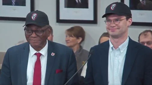 UNMC Chancellor Dele Davies, MD, and UNMC student regent Brock Calamari sing the UNMC fight song at a University of Nebraska Board of Regents meeting.