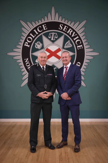 Chief Constable Jon Boutcher standing with Detective Chief Inspector McBurney in front of the Police Service of Northern Ireland crest.