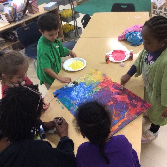 Children in a classroom working on a piece of artwork together.