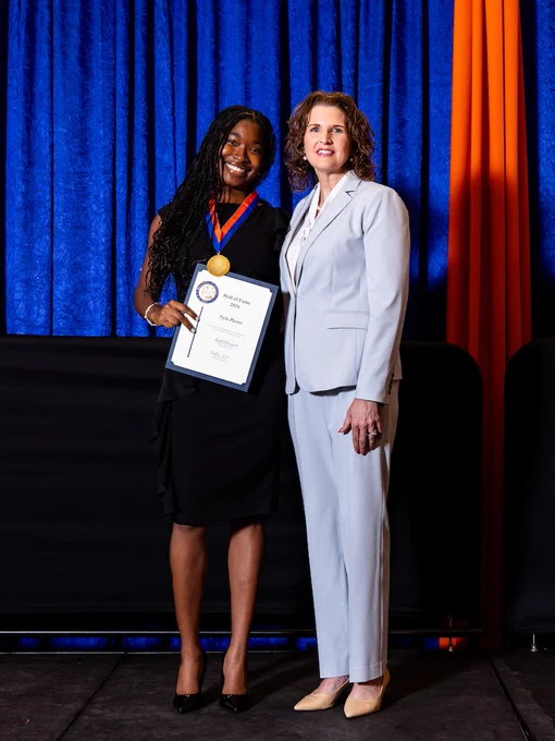 Nyla Pierre poses with a university official while holding her Hall of Fame certificate and medal at the UF Hall of Fame ceremony.