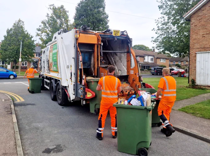 Dustbin lorry with binmen in a street.