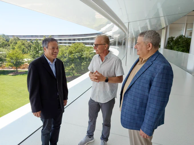 Joz stands in between Jennison Asuncion and Joe Devon as the three chat in the hallway at Apple Park.