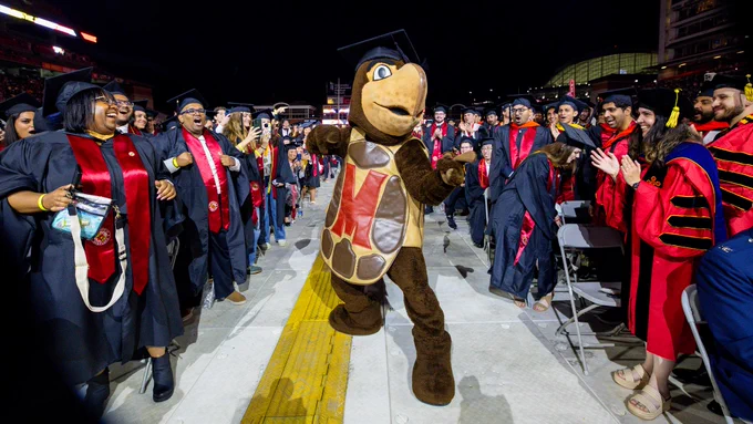 Testudo runs through the crowd of graduates at commencement