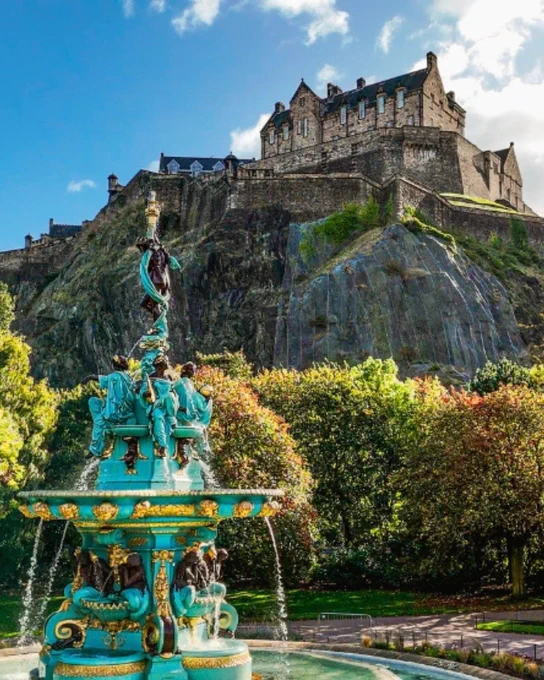 A view of Edinburgh castle  with a fountain in front