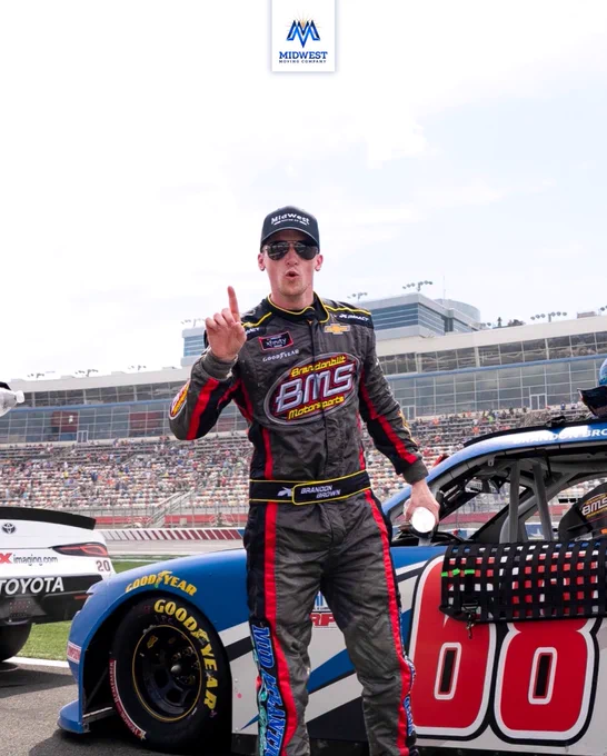 NASCAR driver Brandon Brown wearing a Midwest Moving Company hat, standing on pit road in front of his No. 68 Brandonbilt Motorsports Chevrolet Camaro at Charlotte Motor Speedway after finishing 4th in the 2021 NASCAR Xfinity Series race on Memorial Day Weekend.