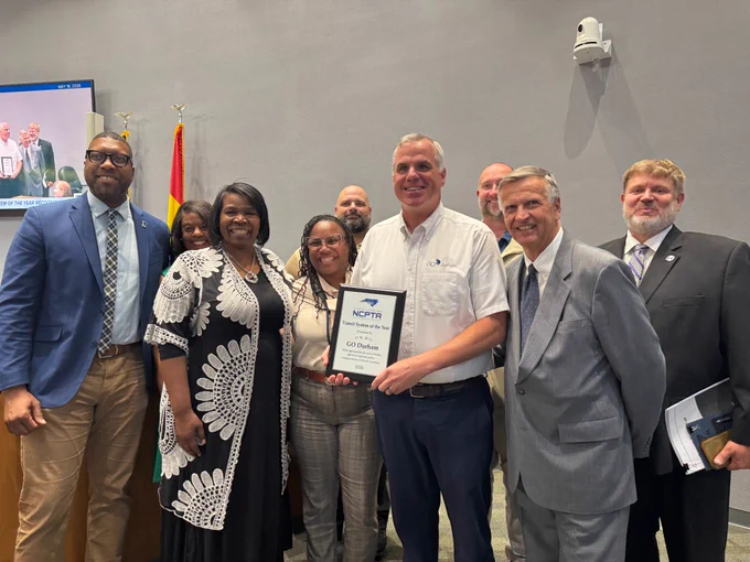 Group photo of Mayor Williams, Transportation Staff from the City and GoDurham, and representatives from the North Carolina Public Transportation Association (NCPTA). Everyone is smiling as Director of Transportation Sean Egan holds up the award plaque. 