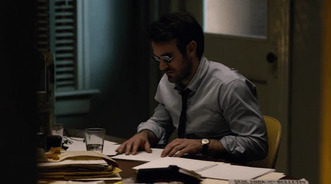 Matt reading Braille at his desk in the original Daredevil season one.