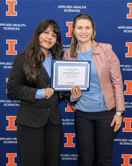 Fatima Pantoja-Lara holding scholarship award posing alongside faculty member at Illinois reception