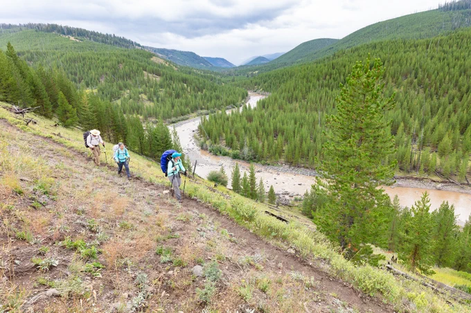 Hikers walking on a dirt trail that overlooks a river