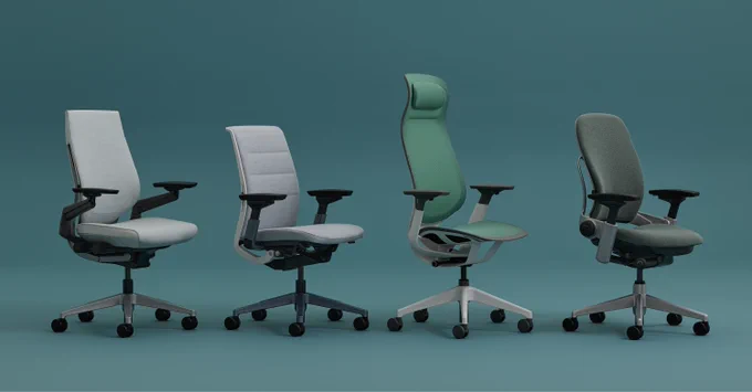 Four ergonomic office chairs in different shades and designs arranged in a row against a teal background.