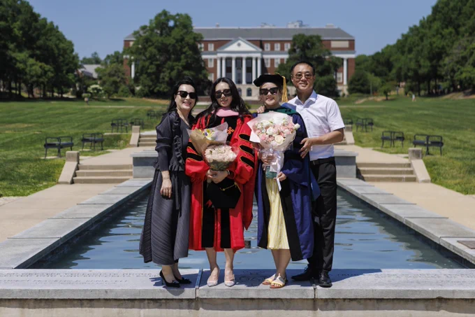 A Terp graduate poses with family on the ODK Fountain on McKeldin Mall
