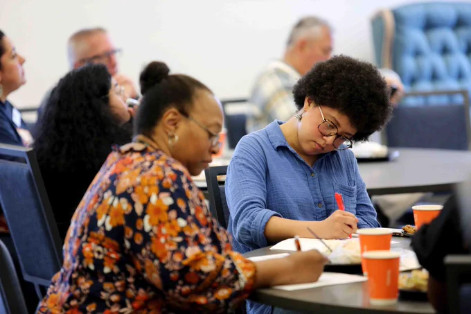 Pictured is a photo of two people taking part in an activity in the Lunch and Learn event. They are seen writing on a piece of paper.