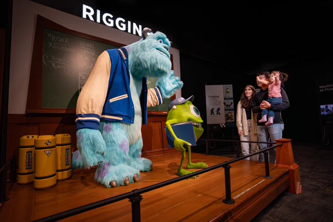 Two parents and a young child looking at statues of Sully and Mike from Monsters Inc