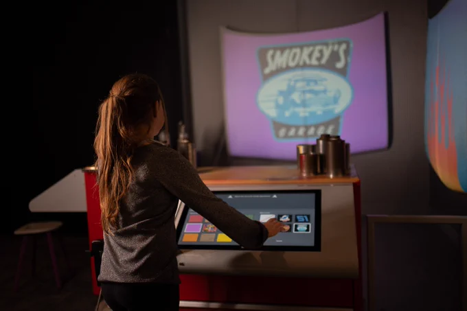 A young guest tapping on a screen to change the design of a hood from Cars