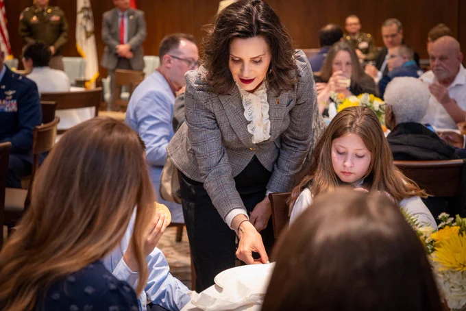 Gov. Whitmer places an object on a families table.