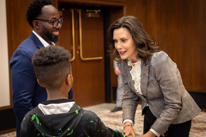 Gov. Whitmer shakes the hand of a kid.