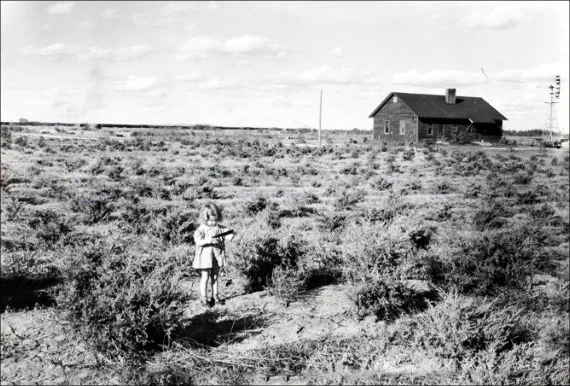 The Denbigh Experimental Forest Sand Hill Station Residence, also known as the Denbigh Station Residence or the Red Forester’s Cabin, is shown in the background with a small child and a Rocky Mountain red cedar plantation in the foreground. Photo taken September 6, 1941.  Photo by J. H. Stoeckeler, National Archives ID: 7061471