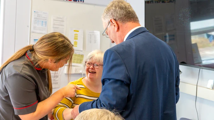 Health Minister Mike Nesbitt holds hands with a smiling service user and staff member at Antrim Adult Centre.