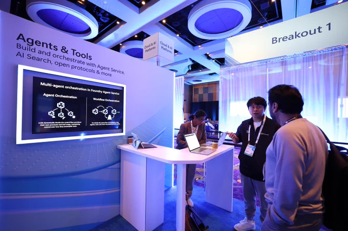 Two men speaking at a hub exhibit at the Microsoft AI Tour
