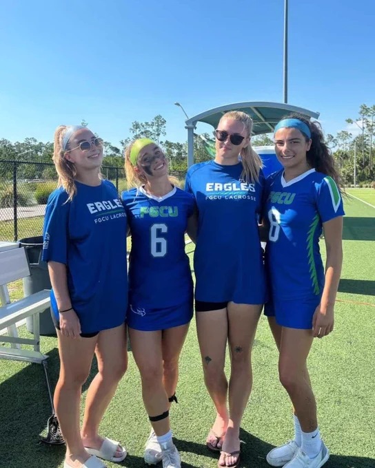 a photo of four fgcu women's lacrosse players smiling on a field 