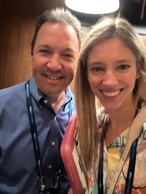 Two people posing for a picture with event lanyards. 