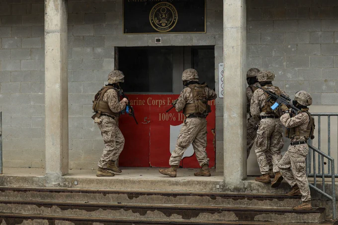 U.S. Marines with 1st Platoon, Guard Company, Marine Barracks Washington, begin to enter a building during civil disturbance training as part of Military Operations in Urban Terrain on Marine Corps Base Quantico, Virginia, May 13, 2026. Civil disturbance training teaches Marines how to employ non-lethal weapons and tactics, enabling them to de-escalate threats and control crowds with minimum force. MOUT provides Marines with the opportunity to refine their urban warfare tactics in a dynamic, real-world setting. Emphasizing speed, precision, and tactical coordination, the Marines worked through a series of challenging exercises, including room clearing, security maneuvers, and small unit tactics. (U.S. Marine Corps photo by Lance Cpl. Landon Heredia)\n\n