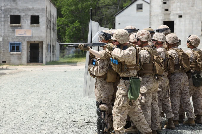 U.S. Marine Corps Lance Cpl. Nathaniel E. Yingling, a security force guard with 1st Platoon, Guard Company, Marine Barracks Washington, aims down the sights of his Mosberg 500 during civil disturbance training as part of Military Operations in Urban Terrain on Marine Corps Base Quantico, Virginia, May 13, 2026. Civil disturbance training teaches Marines how to employ non-lethal weapons and tactics, enabling them to de-escalate threats and control crowds with minimum force. MOUT provides Marines with the opportunity to refine their urban warfare tactics in a dynamic, real-world setting. Emphasizing speed, precision, and tactical coordination, the Marines worked through a series of challenging exercises, including room clearing, security maneuvers, and small unit tactics. (U.S. Marine Corps photo by Lance Cpl. Landon Heredia)\n\n