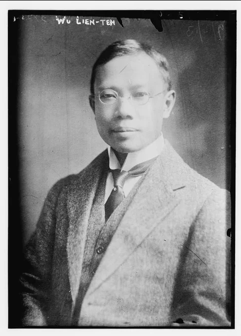A black and white portrait photograph of Wu Lien-teh wearing a formal early-20th-century suit, tie, and round wireframe glasses. He faces the camera with a calm, composed expression. The image has visible scratches and film marks, giving it an archival, historical appearance. Handwritten text at the top reads "Wu Lien-Teh."