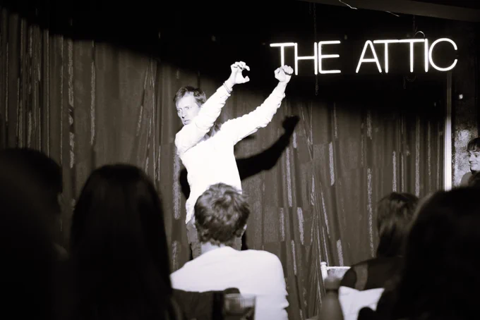 One person onstage. They have their hands in front of them and are gripping an imaginary rail. They look to the side, shocked and processing what they have just witnessed.