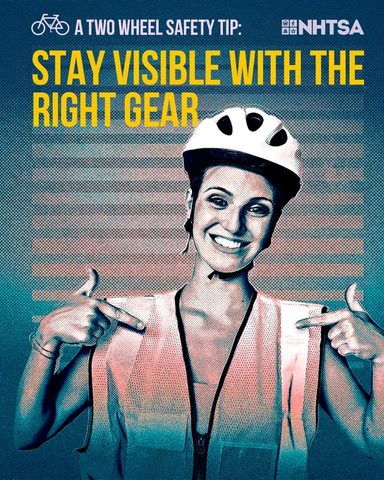 A cyclist wearing a helmet pointing to the reflective vest she has on.