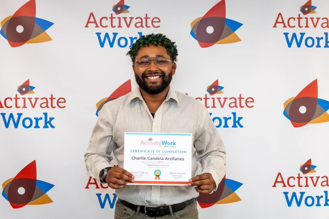 Person holding a certificate of completion from Activate Work, standing in front of a branded backdrop with the ActivateWork logo.