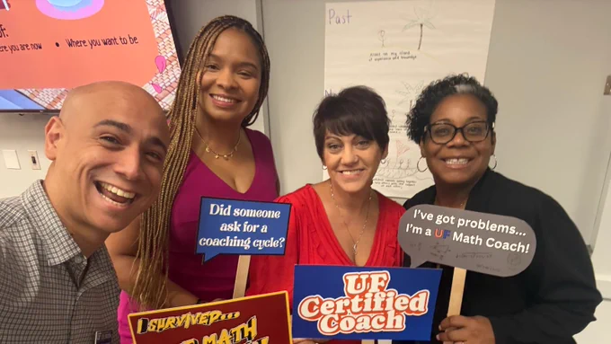 Four people smiling and standing while holding photo props.