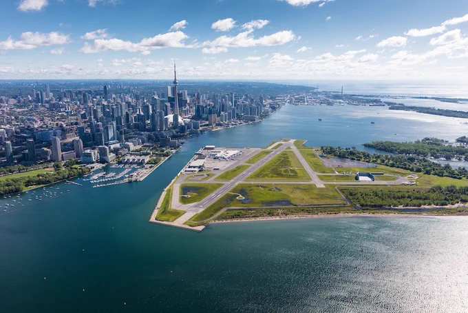 Aerial view of Toronto's downtown skyline with the CN Tower and Billy Bishop Toronto City Airport runway on the waterfront.