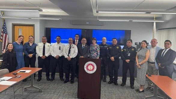 Group of 15 people stand for a photo behind a podium at the Middlesex District Attorney's Office
