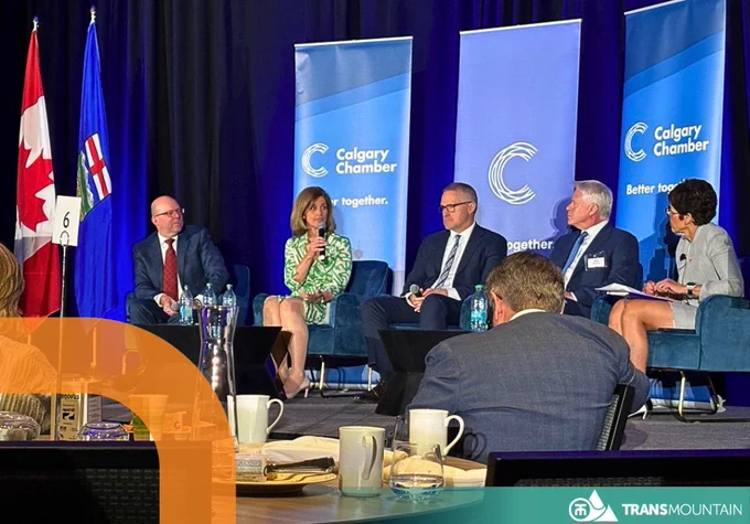 Panel discussion at a Calgary Chamber event with five professionals seated on stage under Canadian and Alberta flags. 