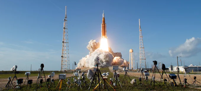 A photo of NASA’s Space Launch System (SLS) rocket lifting off from the launch pad, sending the Artemis II crew on their flight around the Moon. Numerous cameras are pointing toward the rocket in the foreground. Credit: NASA/Aubrey Gemignani