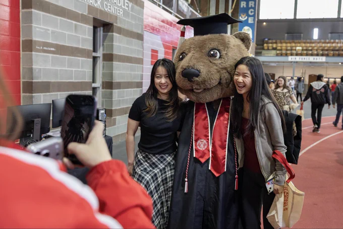 Cornell’s Touchdown mascot gets his picture taken with two graduating Cornellians. Touchdown is wearing Commencement robes.