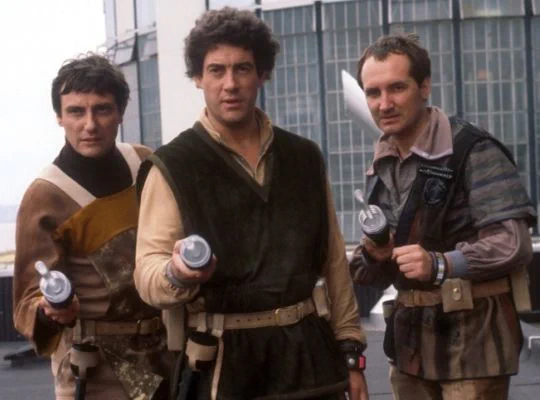 Michael Keating (right) as Vila Restal in Blake's 7, with Paul Darrow (left) as Kerr Avon and Gareth Thomas (centre) as Roj Blake. Keating was the only actor to appear in all 52 episodes of the series from 1978 to 1981.