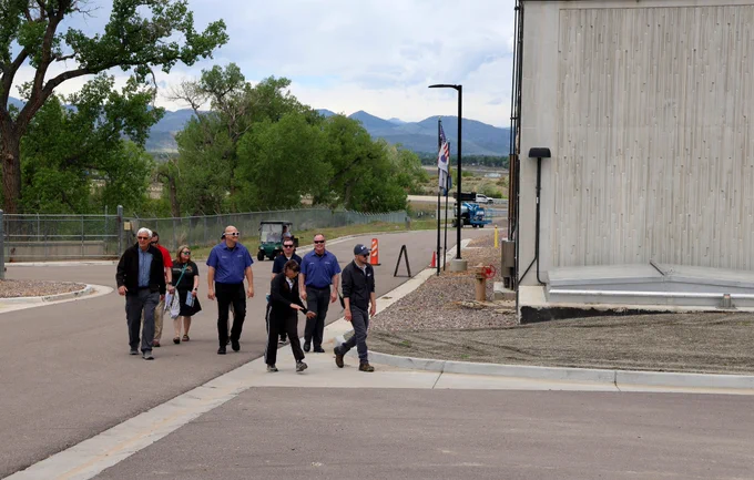 Group of eight people walking along a road next to a tall building at a wastewater treatment plant.