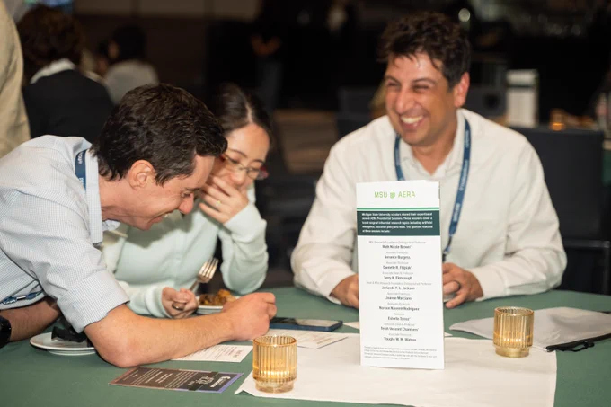 Three Spartans laugh while sitting at a table