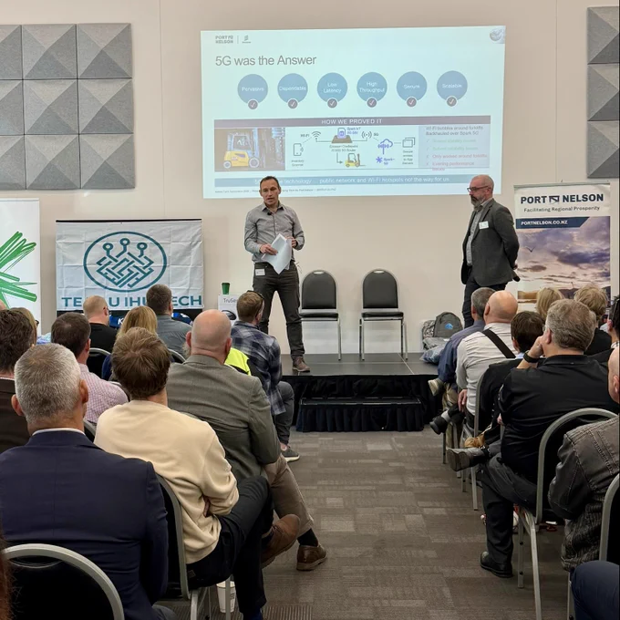 Reagan Pattison from Port Nelson and Ian Ross from Ericsson Enterprise Wireless Solutions present a private 5G deployment case study at an industry symposium. The presentation explains how Port Nelson replaced unreliable warehouse Wi-Fi with a secure private 5G network to improve inventory scanning, mobility, operational efficiency, and real-time connectivity across port facilities.